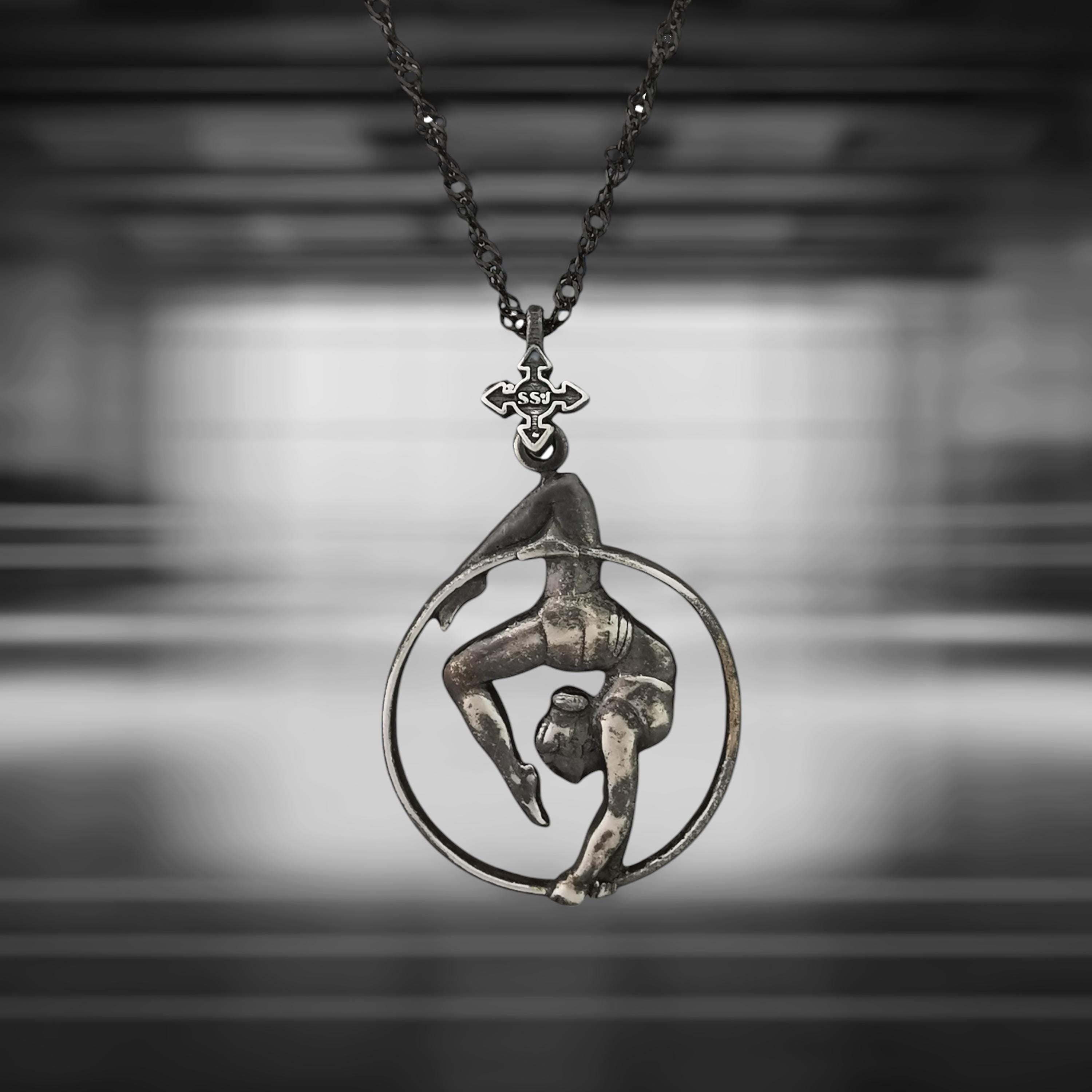 Vintage-style aerial hoop necklace in patinated 925 sterling silver — a bold and soulful pendant capturing the expressive grace of aerial performance. Designed for women who blend movement with meaning, elegance with strength.
This handcrafted piece features a female aerialist mid-performance in an upside-down pose, radiating poise, power, and emotional depth. The aged silver finish adds timeless charm and artistic character — perfect for free spirits and lovers of vintage aesthetics.